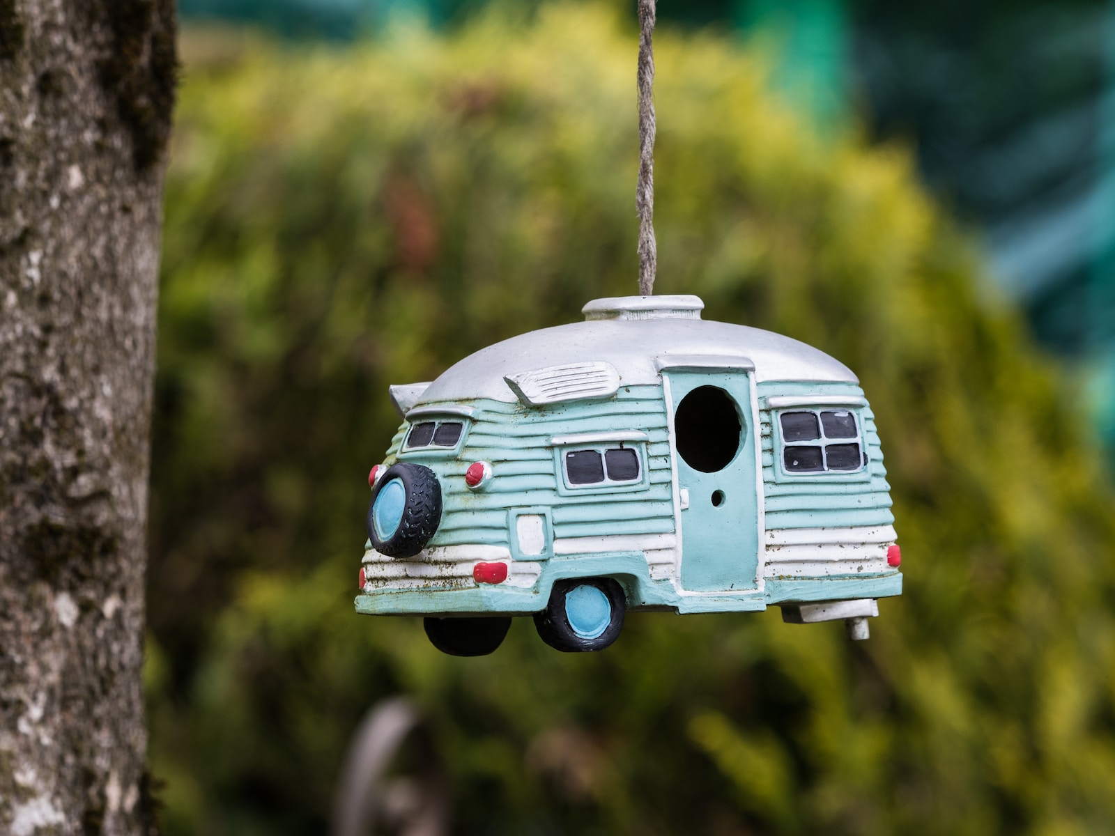 a blue and white camper ornament hanging from a tree